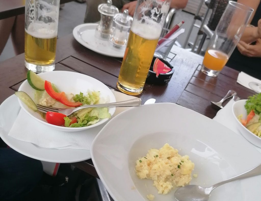 Das Foto zeigt einen Tisch, darauf 2 Biergläser, ein fast leerer Spinat-Risotto-Teller, ein Salat.