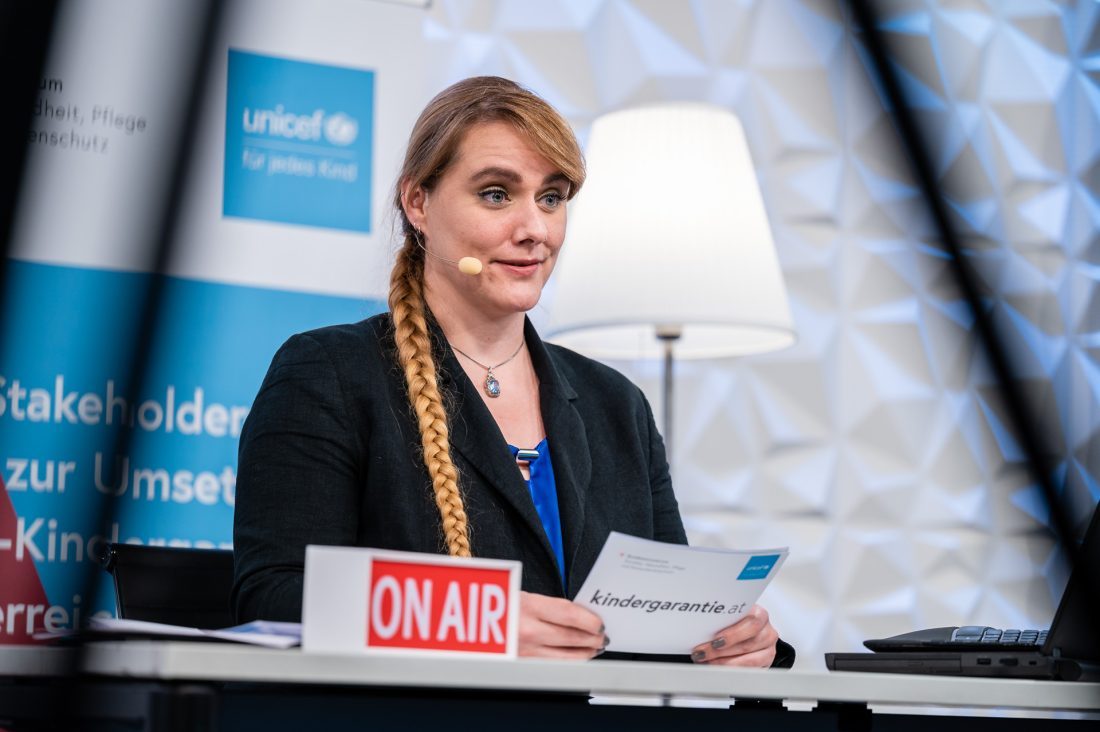 Das Bild zeigt Lorena, sitzend an einem Tisch, sie hat ein Headmikro und Moderationskarten in der Hand. auf dem Tisch steht ein Schild "on air"