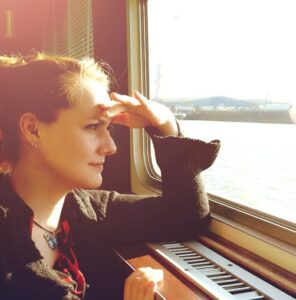 Frau blickt ruhig aus dem Fenster auf das Wasser, kurz vor einer tiefgreifenden Lebensveränderung