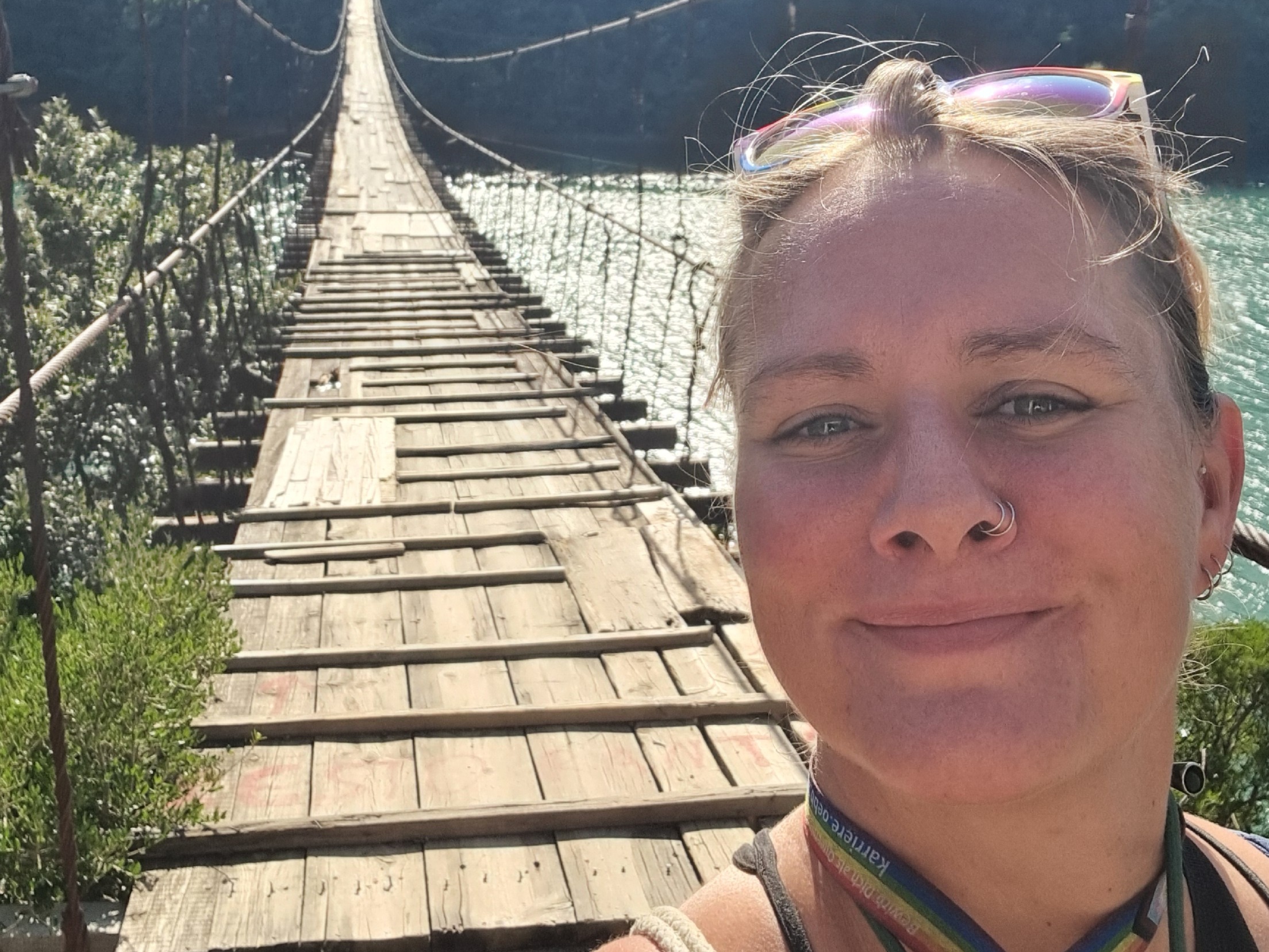 20250902_160150 Frau auf einer schmalen Hängebrücke über einem Fluss, Blick in die Kamera – Sinnbild für Übergang, Vertrauen und den Mut, den eigenen Weg zu gehen.