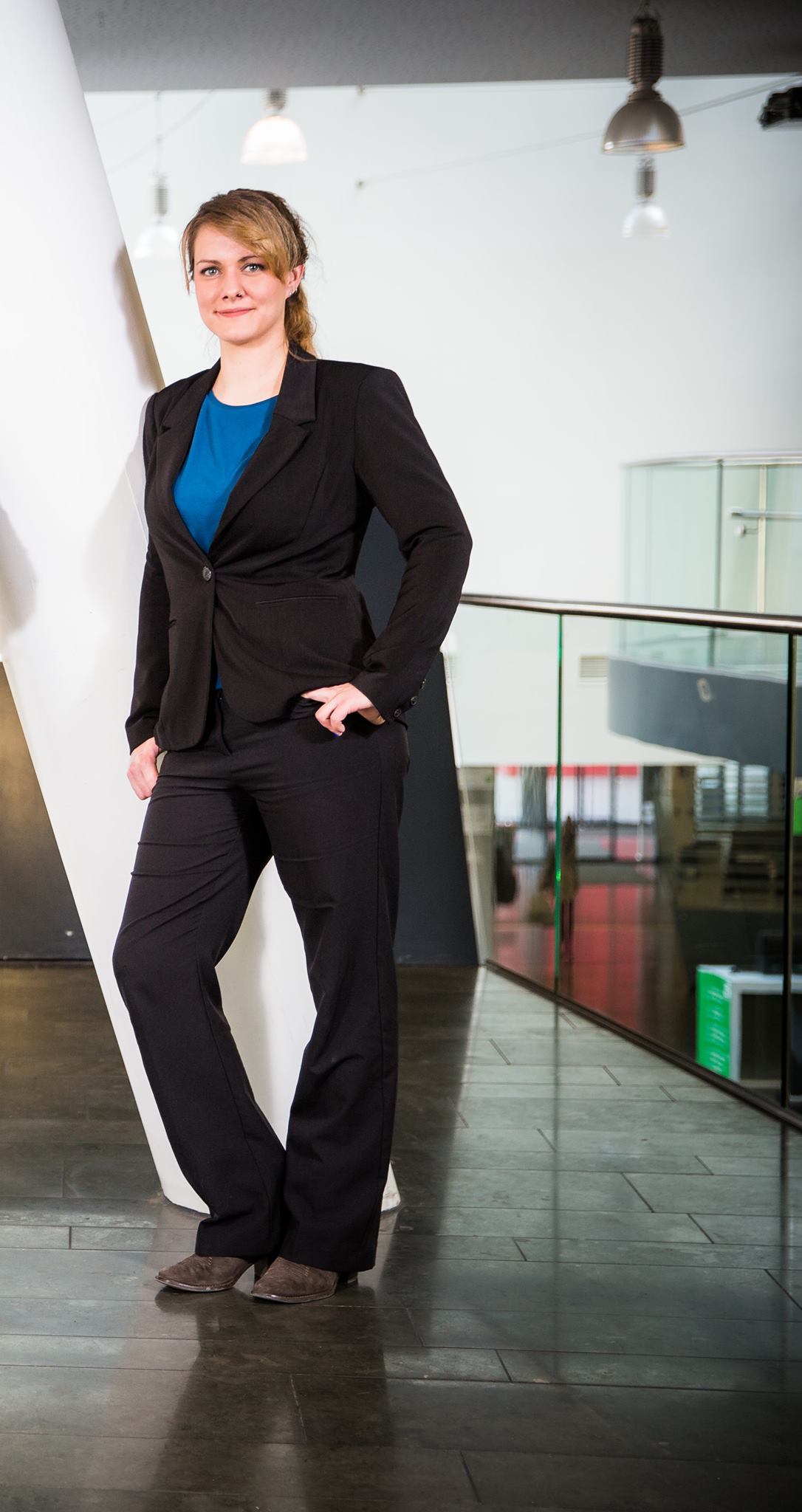 Businessporträt einer Frau im Anzug, souveräner Stand in moderner Architektur